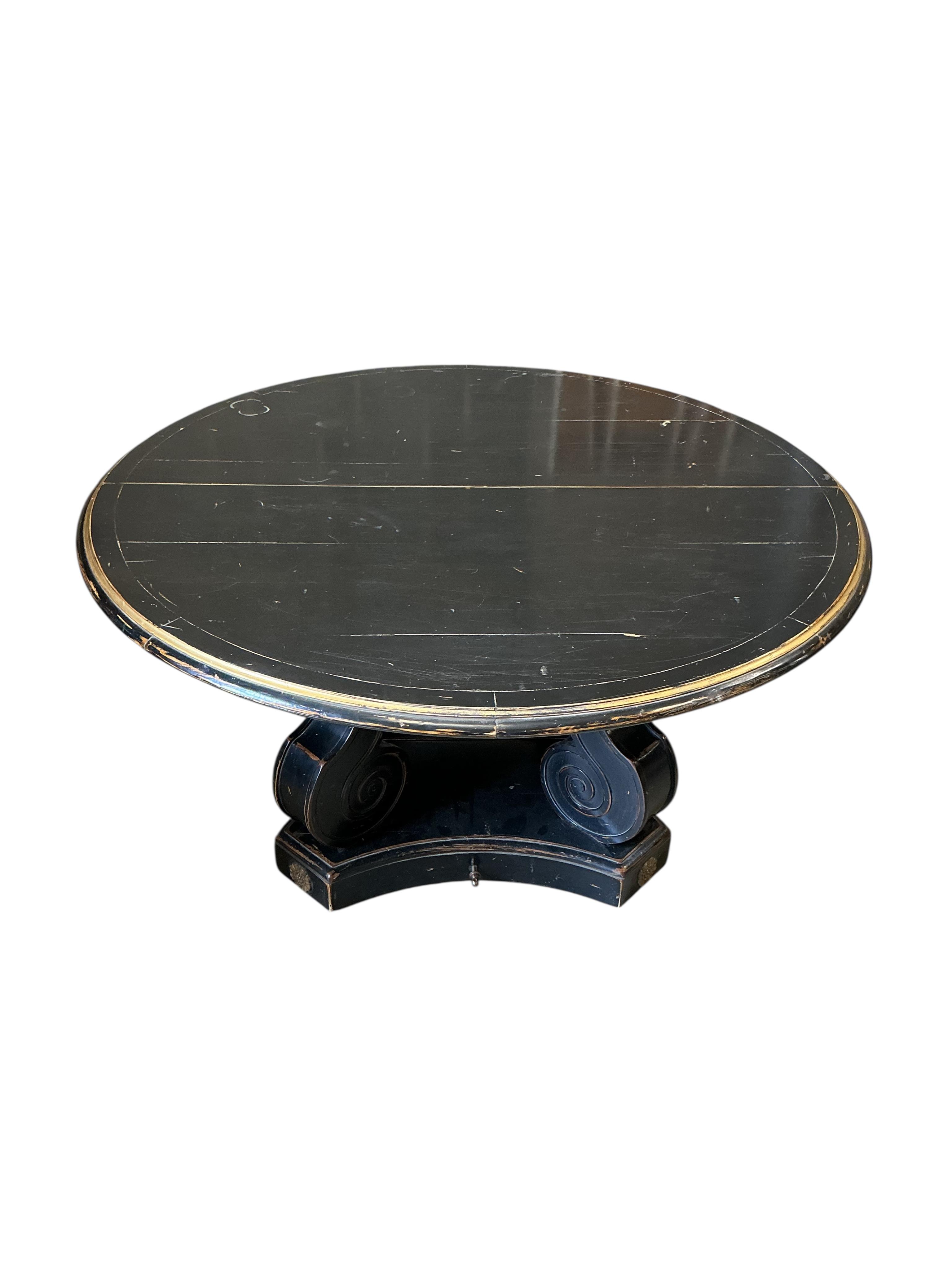 A Regency style ebonised, parcel gilt extending dining table, purchased from Liberty, diameter 150cm, 305cm extended three spare leaves, height